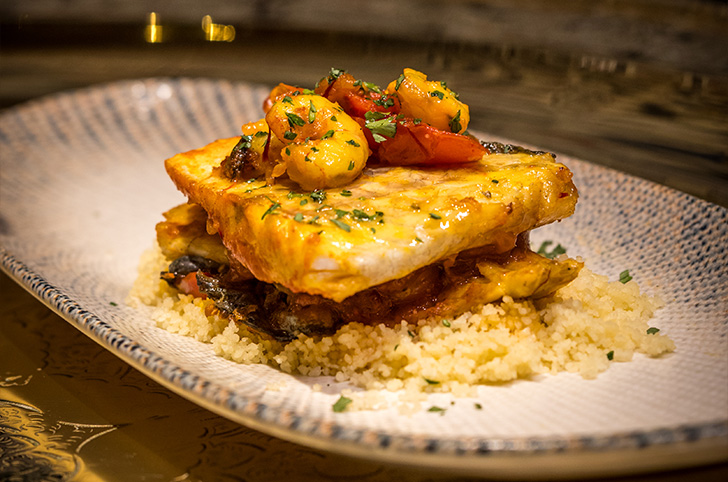 Tajín de pescado con gambas y tomate cherry sobre cous cous en plato marroquí - Al-Mounia Madrid
